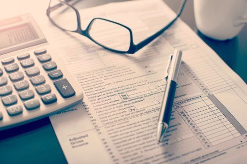 Close up of documents with calculator, pen, and glasses on top