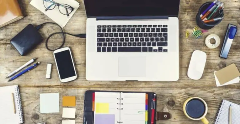 Mix of office supplies and gadgets on a wooden desk background. View from above.